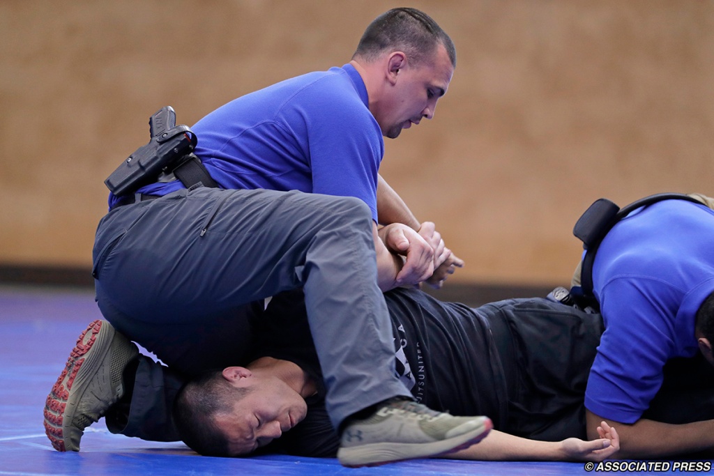 Officers training jiu-jitsu kimura control holds to detain a combative suspect.